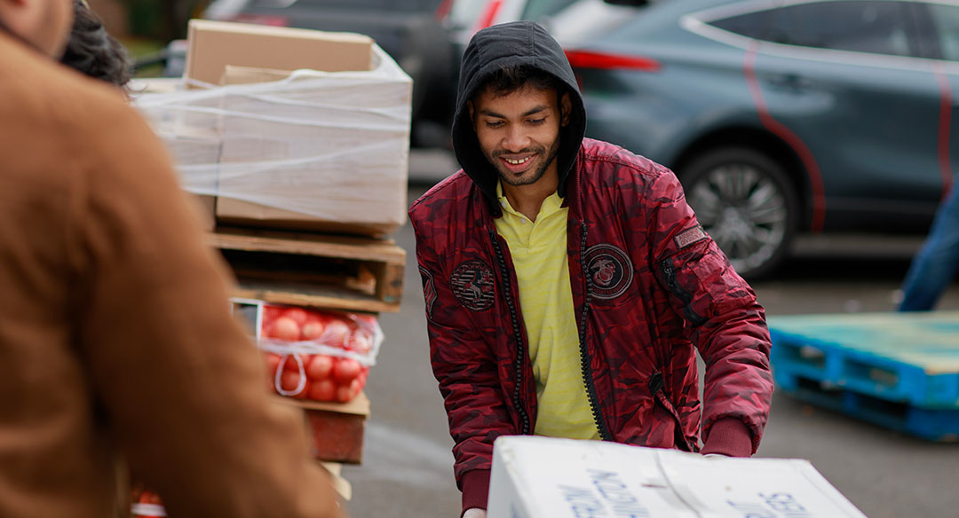 Volunteer smiling and looking down toward boxes.